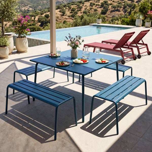 Modernes Gartenmöbel-Set aus Metall mit quadratischem Tisch und vier Bänken auf einer Terrasse neben einem Pool.