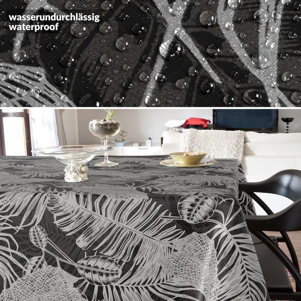 Wasserundurchlässige Tischdecke mit tropischem Blattmuster auf einem Esstisch, Nahaufnahme zeigt Wassertropfen auf dem Material.