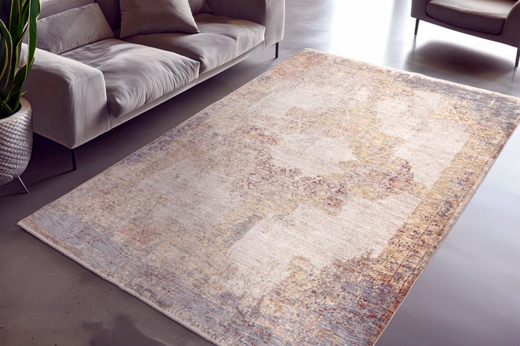 Ein rechteckiger Teppich mit Vintage Muster liegt vor einem Sofa in einem modernen und hellen Wohnzimmer.