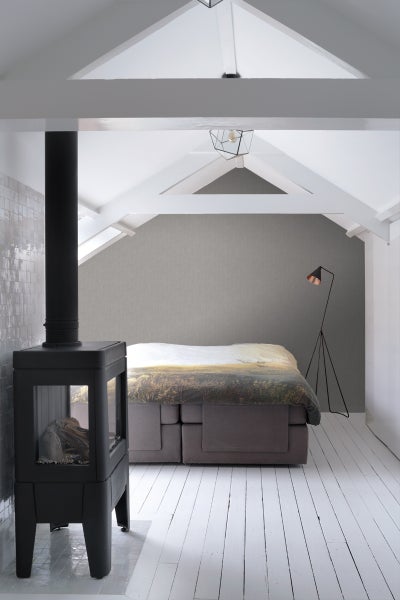 Schlafzimmer mit Kaminofen, Bett und Stehlampe in einem Dachgeschoss