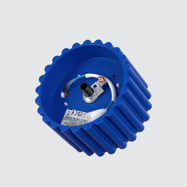 Innenansicht eines blauen, geriffelten Lampensockels mit interner Verkabelung, Elektroanschluss und technischen Etiketten.