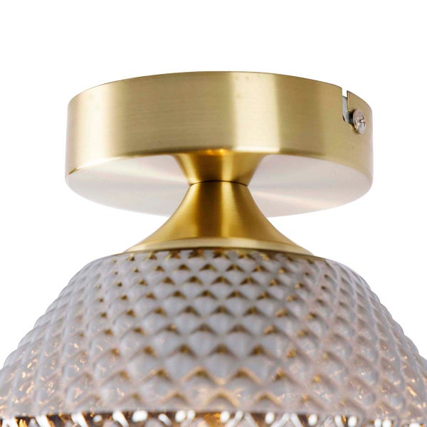 Nahaufnahme einer Deckenleuchte mit klarem, gemustertem Glasschirm und goldfarbener Halterung
