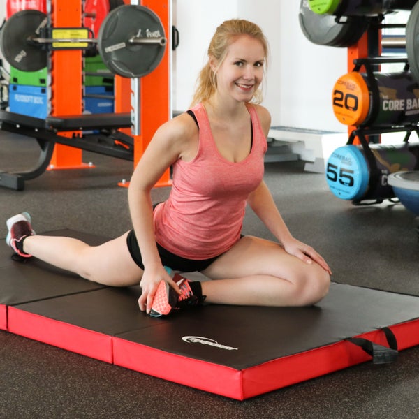 Frau dehnt sich auf einer Gymnastikmatte im Fitnessstudio.