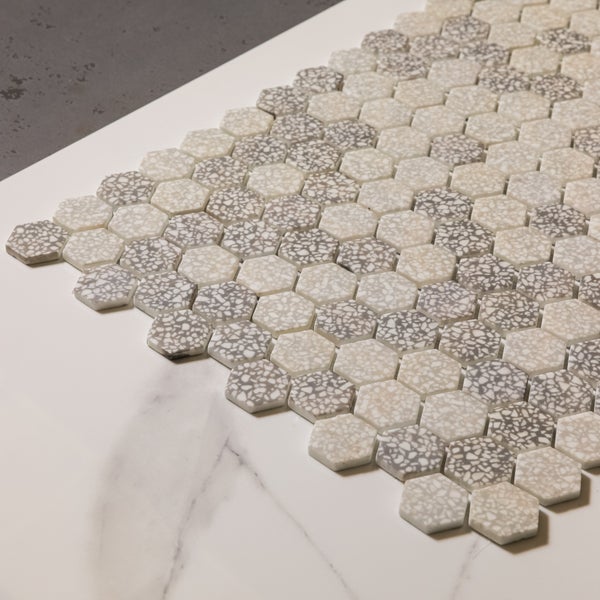 Sechseckige Mosaikfliesen mit Terrazzo-Optik auf hellem Untergrund.