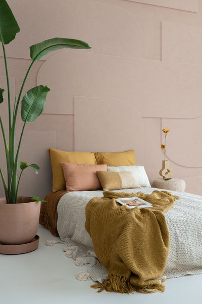 Schlafzimmer mit Bett, Kissen, Decke und Zimmerpflanze