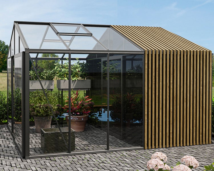 Modernes Gewächshaus aus Glas und anthrazitfarbenem Aluminium kombiniert mit einem Holzlamellenanbau auf einer gepflasterten Fläche.
