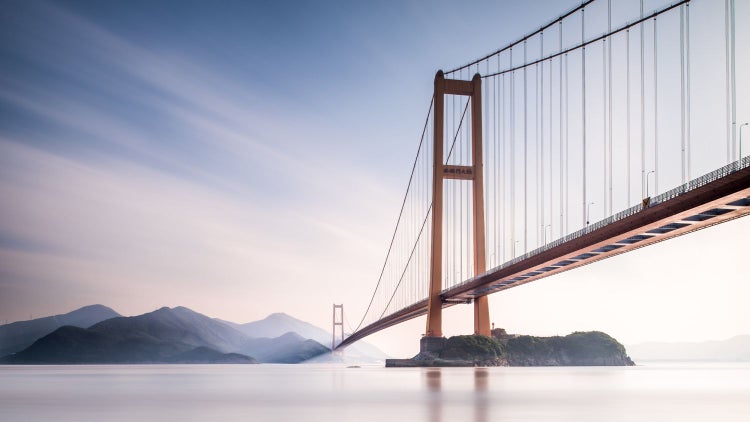 Hängebrücke über dem Wasser mit Bergkette im Hintergrund