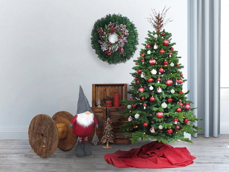 Festlich geschmückter Weihnachtsbaum mit Adventskranz und Wichtelfigur vor einer Holzholzkiste und einer Kabeltrommel als Weihnachtsdekoration.