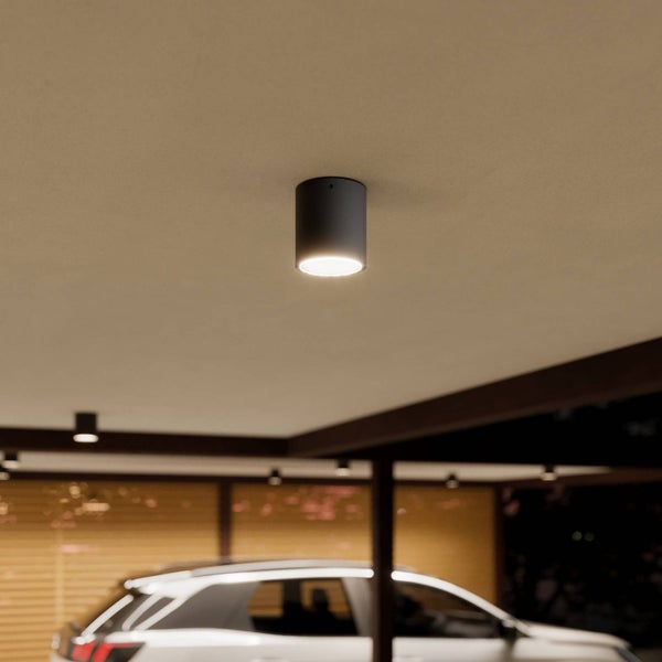 Zylindrische Anbauleuchte an einer Carport-Decke. Modernes Design mit hellem Lichtstrahl über einem Fahrzeug.