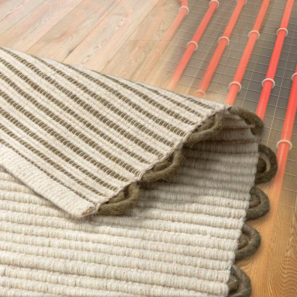 Strukturierter gewebter Teppich auf Holzboden, teilweise umgeklappt zur Darstellung der Eignung für Fußbodenheizung.