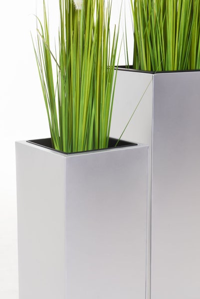Künstliches Gras in quadratischen silberfarbenen Pflanzsäulen aus Metall.