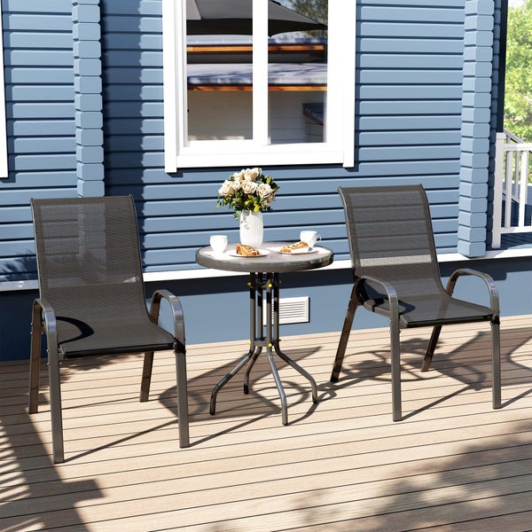 Zwei stapelbare Gartenstühle und ein runder Bistrotisch aus Metall auf einer Holzterrasse vor einem blauen Holzhaus.