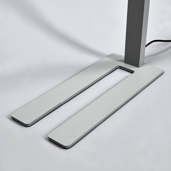 Grauer, flacher, U-förmiger Metallstandfuß einer Stehleuchte mit rechteckigem Rohr und schwarzem Kabel.
