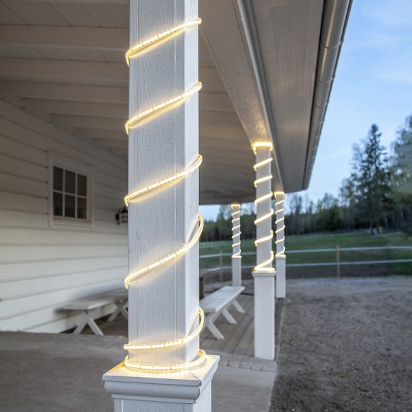 Veranda mit weiß gestrichenen Säulen, um die eine Lichterkette gewickelt ist