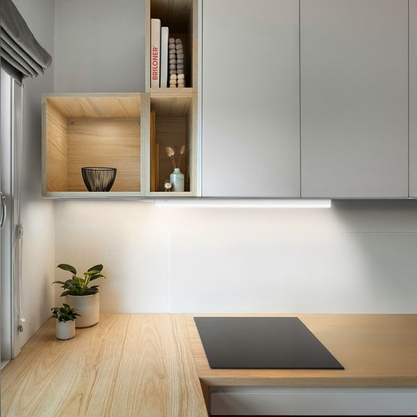 Helle moderne Küche mit Holz-Arbeitsplatte, Kochfeld und LED-Unterbauleuchte unter Wandschränken und Holzregalen.