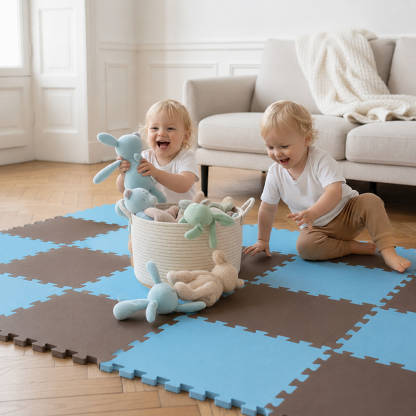 Zwei Kleinkinder spielen auf einer quadratischen Puzzlematte aus Schaumstoff mit einem Korb voller Plüschtiere in einem hellen Wohnzimmer.