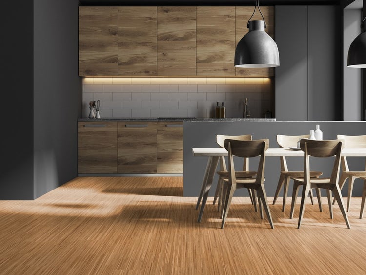 Moderne Küche mit Holzfronten, weißen Fliesen und Essbereich mit Holztisch und Stühlen auf Bodenbelag in Holzoptik.