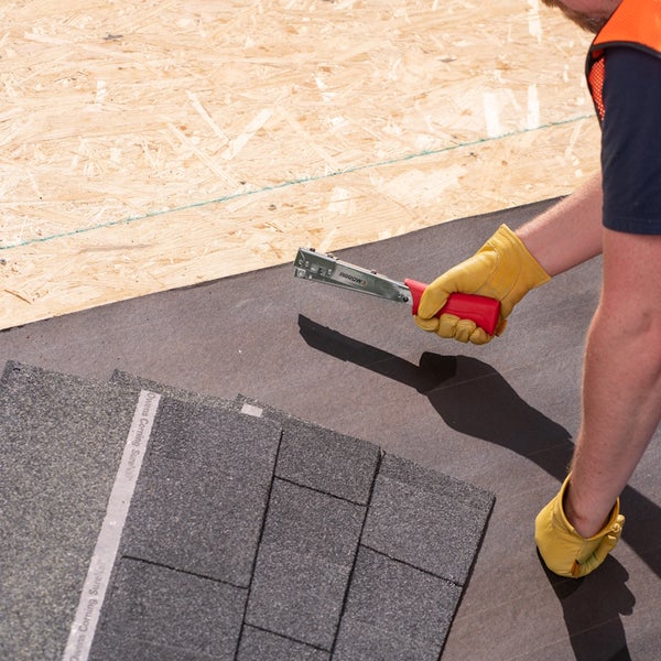 Hammertacker wird verwendet, um Dachpappe auf einer OSB-Platte zu befestigen.