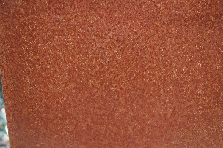 Detailansicht einer gerosteten Metalloberfläche mit einer gleichmäßigen, oxidierten Struktur.