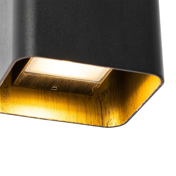 Nahaufnahme einer modernen Wandleuchte mit schwarzer Außenseite, goldfarbener Innenseite und integriertem Leuchtmittel.