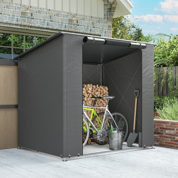 Dunkelgraues Garten-Lagerzelt mit aufrollbarer Front, bestückt mit Fahrrädern, Kaminholz, einer Schaufel und einem Eimer an einer Hauswand.