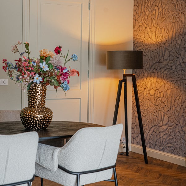 Esszimmer mit Tisch, Stühlen, Blumenstrauß in goldener Vase und Stehlampe