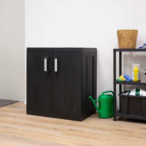 Schwarzer Kunststoffschrank mit zwei Türen und silberfarbenen Griffen steht in einem Raum.