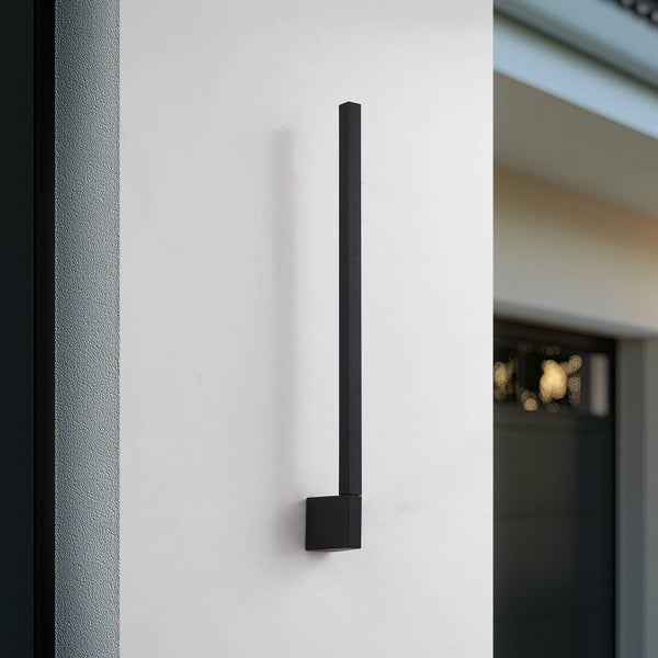 Moderne schwarze LED-Wandleuchte in Stabform an einer Hauswand.