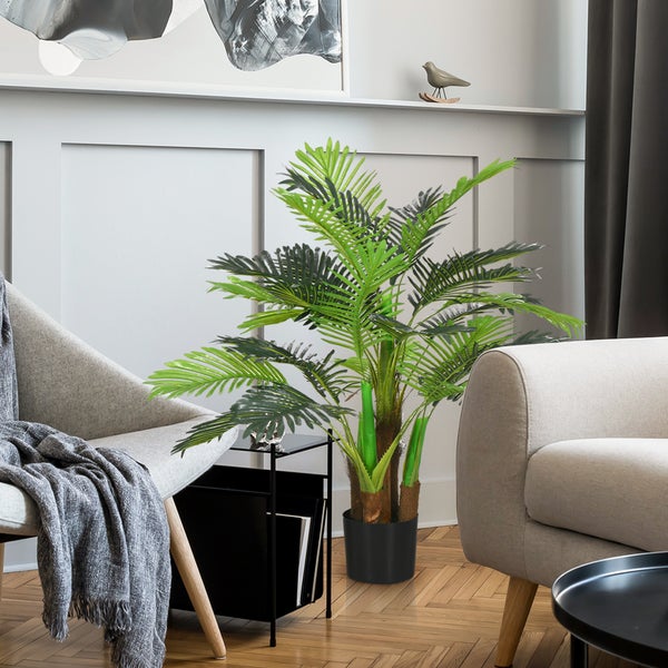 Dekoratives Zimmer mit Kunstpalme im Topf zwischen Sessel und Sofa.