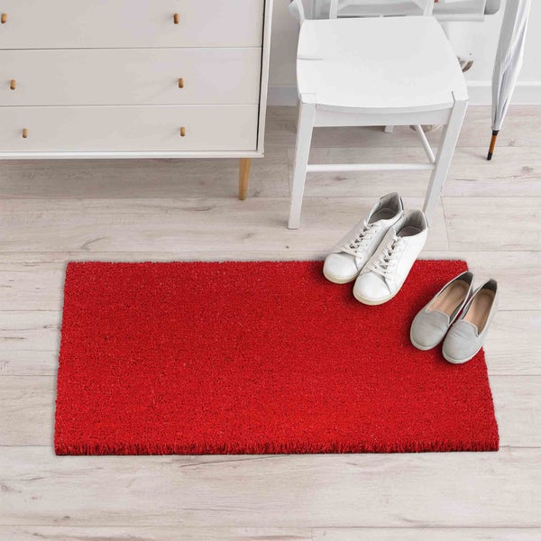 Roter Fußabtreter aus Kokosfasern vor einer Tür