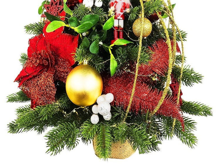 Künstlicher Weihnachtsbaum im Topf dekoriert mit Christbaumkugeln Mistelzweigen und Nussknacker Figur als festliche Tischdekoration
