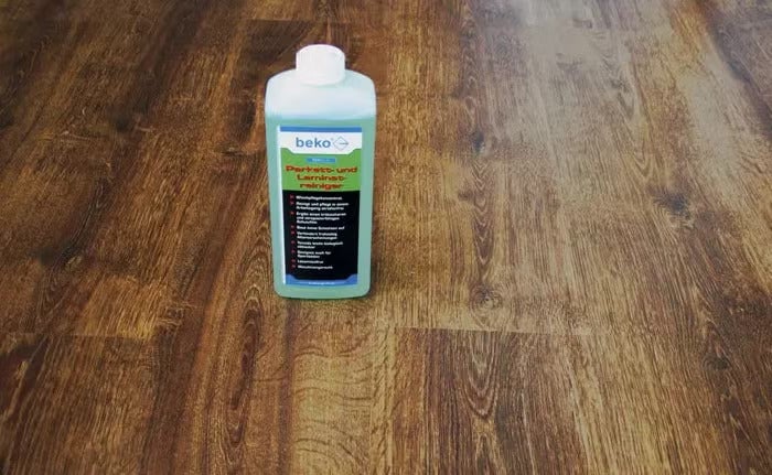 beko Parkett- und Laminatreiniger in Kunststoffflasche auf einem Bodenbelag in Holzoptik.