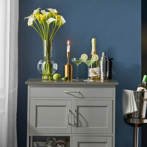 Dekoratives Sideboard mit Blumenstrauß, Kerze und Getränken für eine stilvolle Atmosphäre