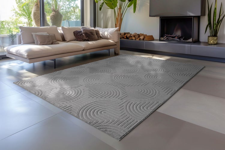 Moderner rechteckiger Teppich mit kreisförmigem Muster im Wohnzimmer vor einem Sofa und Kamin