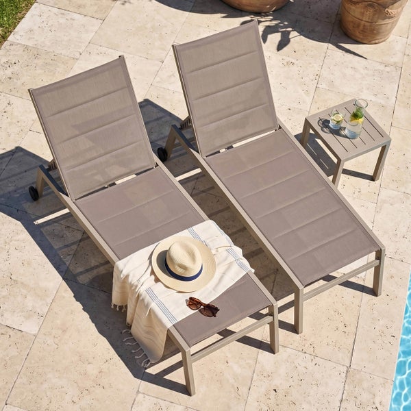 Zwei Gartenliegen mit verstellbarer Rückenlehne und ein passender Beistelltisch auf einer Steinterrasse am Pool.