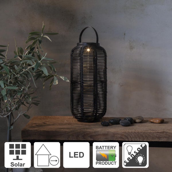 Zwei schwarze geflochtene Laternen auf einem Holztisch