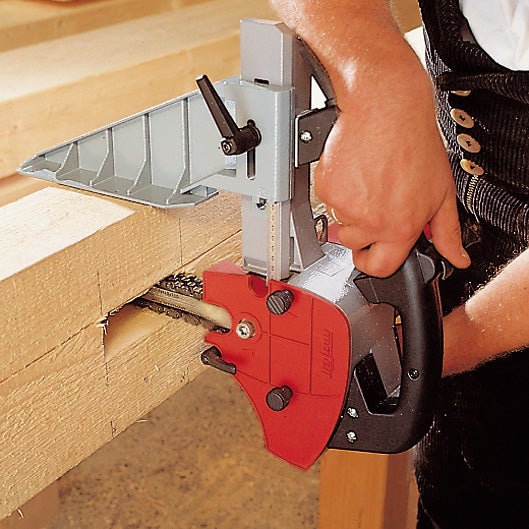 Handwerker verwendet eine Mafell Kettenstemmmaschine zur Bearbeitung eines Holzbalkens in einer Werkstatt.
