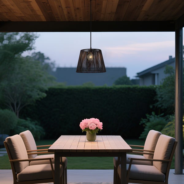 Stimmungsvolle Terrasse mit Holztisch, gepolsterten Stühlen und einer dunklen Hängeleuchte aus Geflecht über dem Esstisch im Freien.