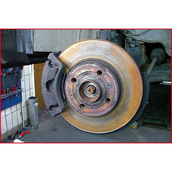 Eine abgenutzte Bremsscheibe mit Bremssattel am Fahrzeug.