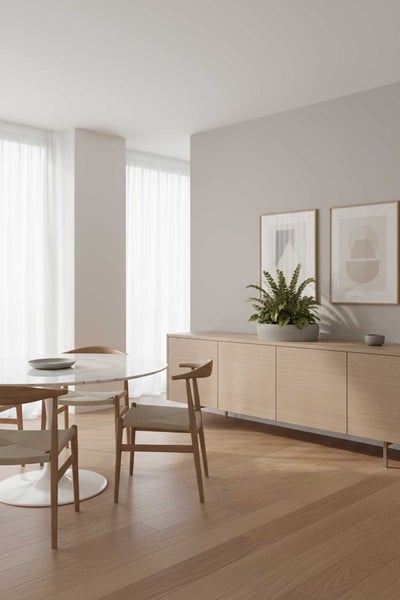 Modernes, helles Esszimmer mit rundem Marmortisch, Holzstühlen und einem Sideboard aus hellem Holz auf Parkettboden.