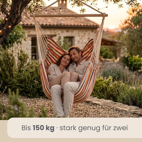 Ein Paar sitzt in einem gestreiften Hängesessel im Garten. Belastbarkeit bis 150 Kilogramm, geeignet für zwei Personen.