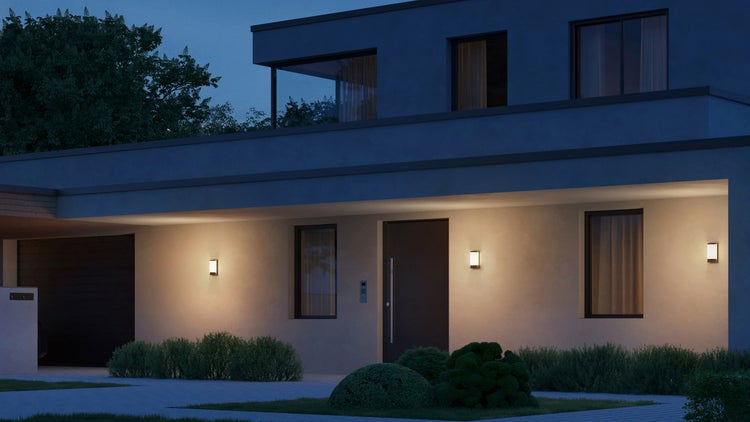 Beleuchtetes modernes Haus mit Außenbeleuchtung und gepflegtem Garten bei Nacht.