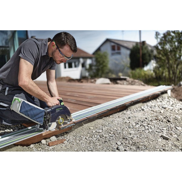 Handwerker schneidet Terrassendiele aus Holz mit einer Festool Handkreissäge auf einer Führungsschiene im Außenbereich.