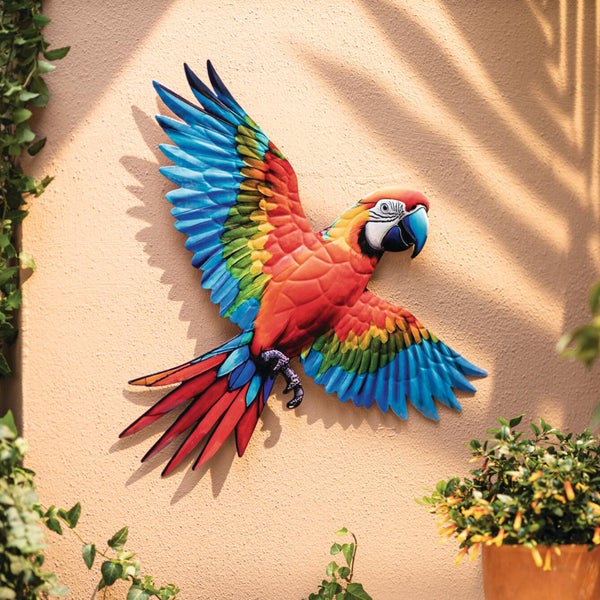 Wanddekoration aus Metall in Form eines bunten Papageis an einer Wand.