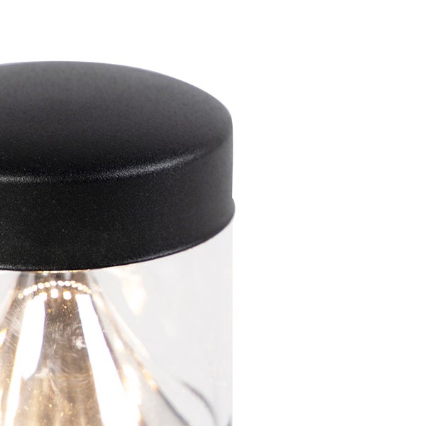 Detailansicht einer zylindrischen Außenleuchte mit schwarzer Metallkappe und klarem Glasdiffusor