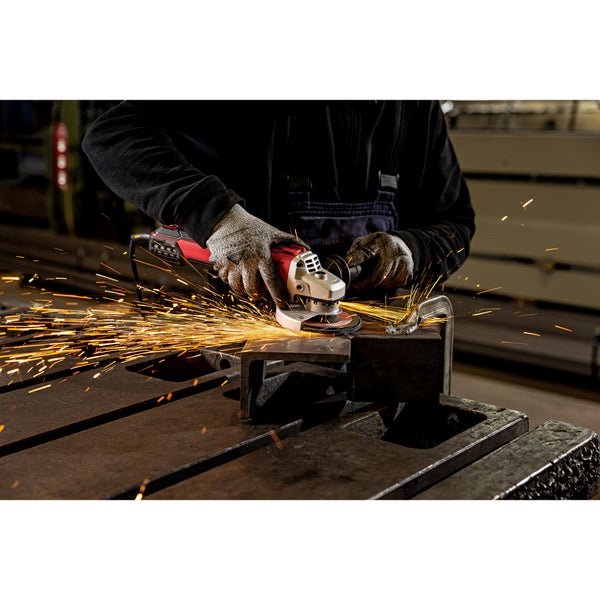 Handwerker bearbeitet ein Metallstück mit einem Winkelschleifer auf einer Werkbank, wobei Funkenflug entsteht.