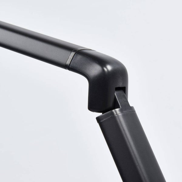 Nahaufnahme eines schwarzen Gelenks, das zwei rechteckige Arme einer Lampe oder eines Halters verbindet.