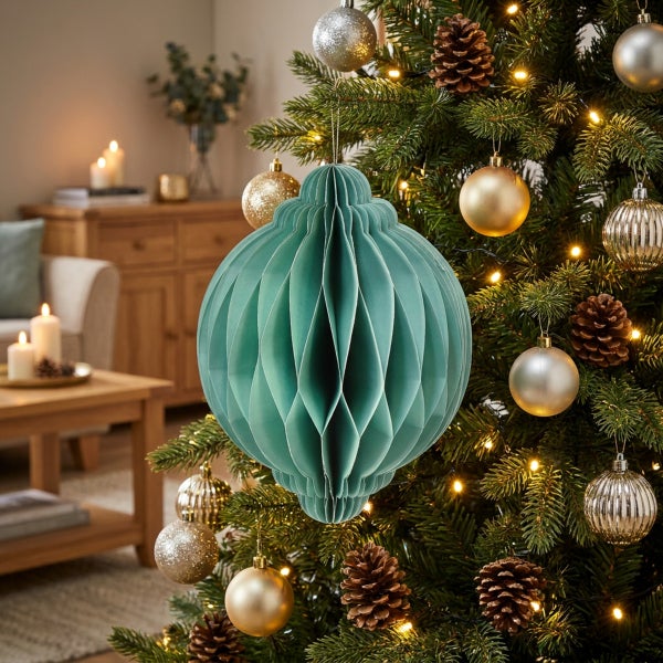 Weihnachtsbaumschmuck aus Papier in Wabenform hängend an einem geschmückten Tannenbaum im Wohnzimmer.