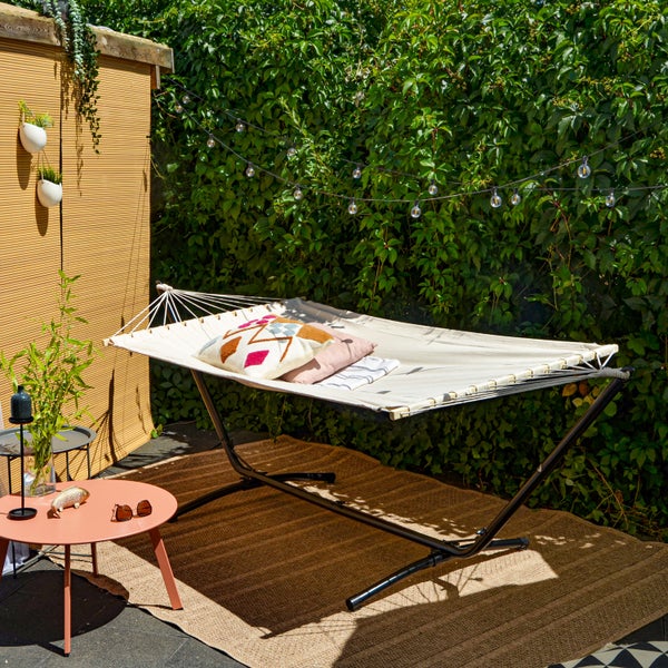 Gartenszene mit Hängematte, Beistelltisch und Outdoor-Dekoration auf einer Terrasse mit Grünpflanzen