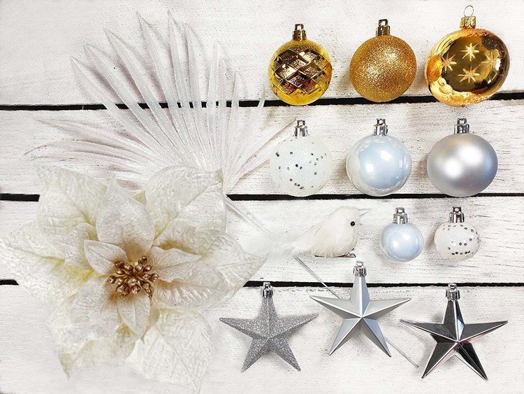 Weihnachtsbaumschmuck Set mit Kugeln, Sternen, einer künstlichen Poinsettia und einem Dekovogel als Set auf rustikalem Holzuntergrund.